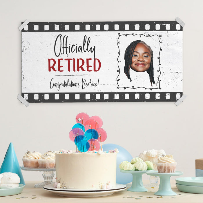 Retirement party display featuring the Officially Retired banner above a celebration table. Custom photo retirement sign shown as a backdrop for cakes, gifts, and party decorations.