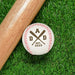 Baseball sits on grass next to baseball bat. Baseball has DAD design engraved on it.