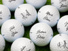 Multiple Titleist golf balls shown with different names on each ball. Golf balls sit on a grassy surface.
