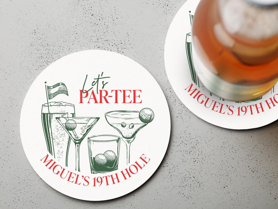 Custom round pulpboard coasters are shown sitting on a light gray stone background with a beer glass on top of one. The custom coasters feature design printed with green sketched cocktails with golf balls and flags within the drinks, and red and green text.