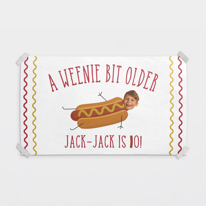 Personalized "A Weenie Bit Older" birthday banner featuring a custom name, age, and face cutout photo.
