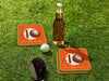 Custom square pulpboard coasters are shown sitting on a grassy, green golf course next to a bottle of beer, white golf ball, and golf club. The coaster features design with illustrated golf ball, custom age and year, and vivid orange, cream, and green background.