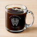 A glass mug filled with a dark liquid, likely coffee, with foam on top. The mug has a personalized message engraved on it, which reads "Happy Mother's Day 2026 Love, Reed".