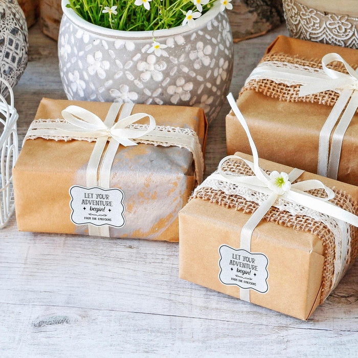 Wrapped wedding gifts tied with ribbon and decorated using personalized “Let Your Adventure Begin” white glitter wedding gift tags. Adds a polished finishing touch to bridal shower and wedding presents.