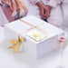 White gift box wrapped with satin ribbon and finished with a personalized gold foil “Your Biggest Fans” wedding gift tag. Elegant packaging inspiration for weddings and special occasions.