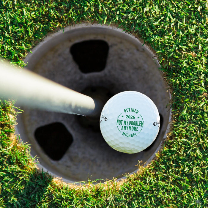 Top view of a personalized retirement golf ball resting in a golf cup. Features a custom name and retirement year design.