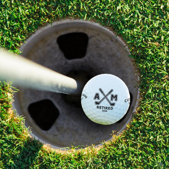 Top view of a personalized retirement golf ball resting in a golf cup. Features the Retired Monogram design with custom initials and retirement year.