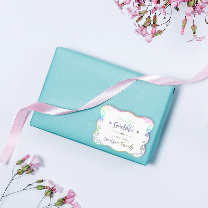 Small pastel gift box wrapped with ribbon and finished using a rainbow foil “Let Love Sparkle” wedding gift tag. A colorful and stylish packaging idea for weddings and celebrations.