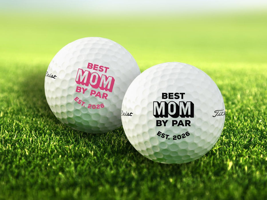 Two golf balls with Best Mom By Par designs printed on them, placed on a grassy field.