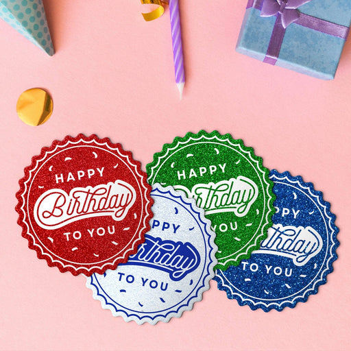 Four Happy Birthday round tags in glitter blue, glitter red, glitter green, and glitter white.