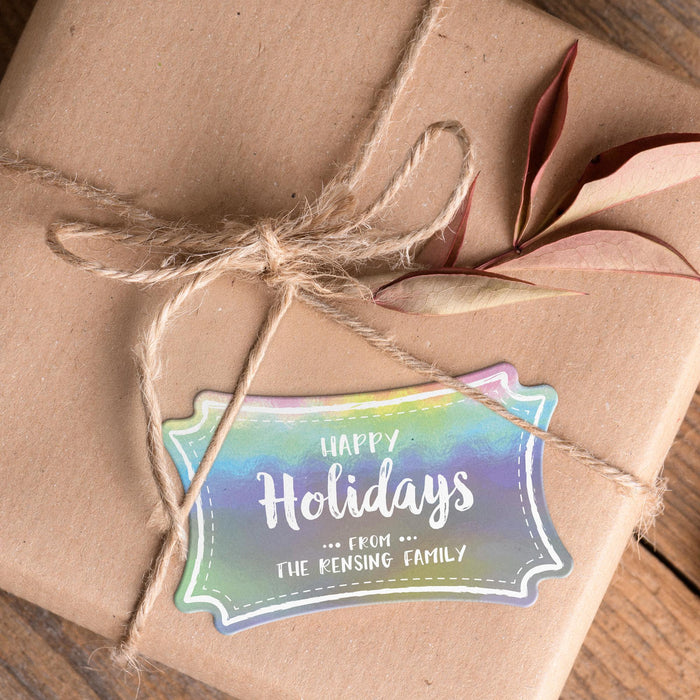 Personalized slim rectangle Christmas gift tag placed on a kraft paper wrapped gift tied with natural twine and dried leaves.
