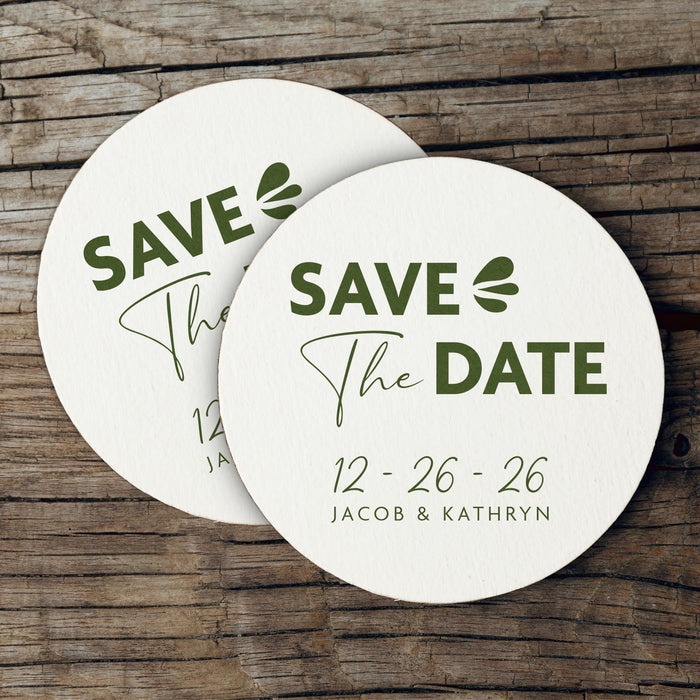 Stack of personalized Save the Date coasters displayed on a rustic wood background. Modern wedding favors customized with names and date.