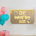 Personalized bee birthday banner hanging on a white brick wall featuring honeycomb accents and custom printed name design.