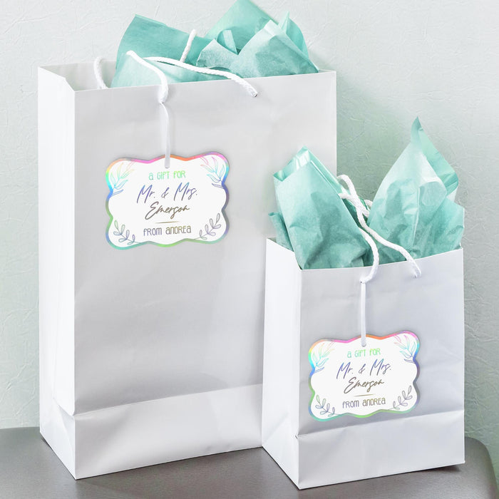 White gift bags with tissue paper featuring personalized “Mr. & Mrs.” holographic foil wedding gift tags. A stylish option for wedding welcome bags, bridal party gifts, and favors.