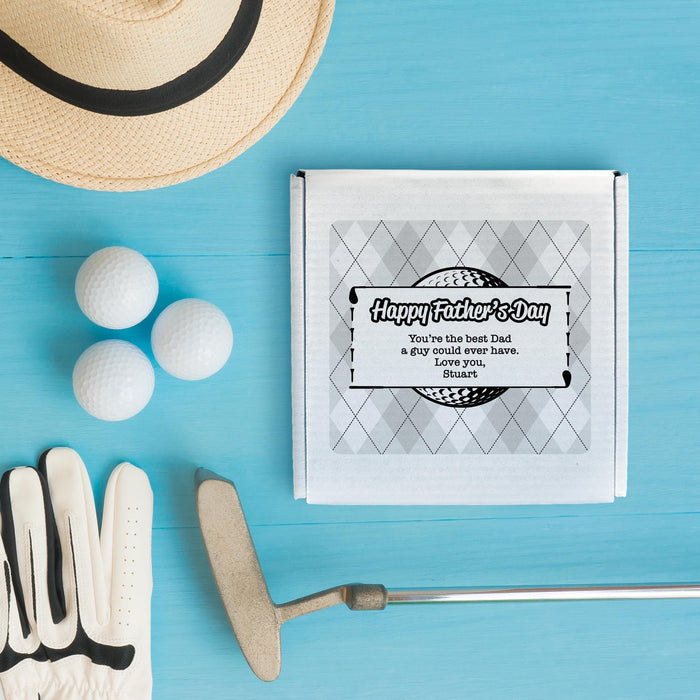 A personalized Father's Day gift box for 3 golf ball sleeves is shown with 3 golf balls and a hat, along with a golf gloves and a golf club, all arranged on a blue background.