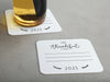 One coaster has a glass on it and an empty coaster sits beside it. Coasters feature the text I'm thankful for, has lines for writing in a response, and current year.