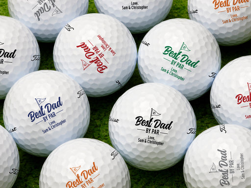 multiple white titleist golf balls with customizable personalized Best Dad By Par designs in different color ontop of golf course grass