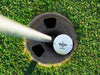 single white titleist golf ball with customizable personalized black Best Dad By Par design in golf course hole next to pole surrounded by grass