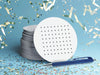 stack of white dots and boxes party game coasters on blue background surrounded by multicolored party confetti and a blue ballpoint pen