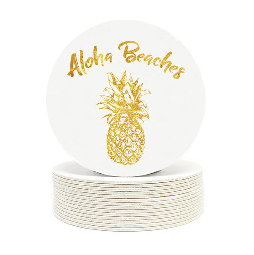 Single coaster is shown on top of a stack of coasters. Coasters are white and feature Aloha Beaches design. Design is printed with a gold texture and shows the words Aloha Beaches and has a pineapple on it.