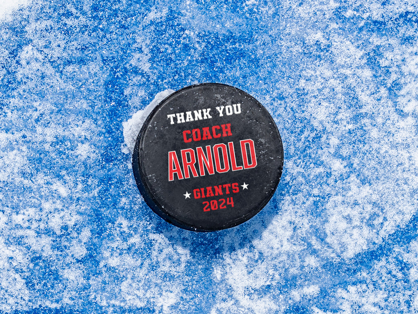 single hockey puck on blue ice rink with a red coach appreciation design that says Thank You Coach Arnold, Giants, 2024
