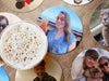various paper photo coasters with pictures of people and pets on wooden table under a glass of beer