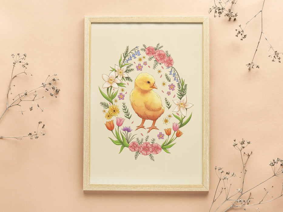 wooden frame with pastel easter art print of a baby chick surrounded by spring flowers on a light orange background with tiny plants