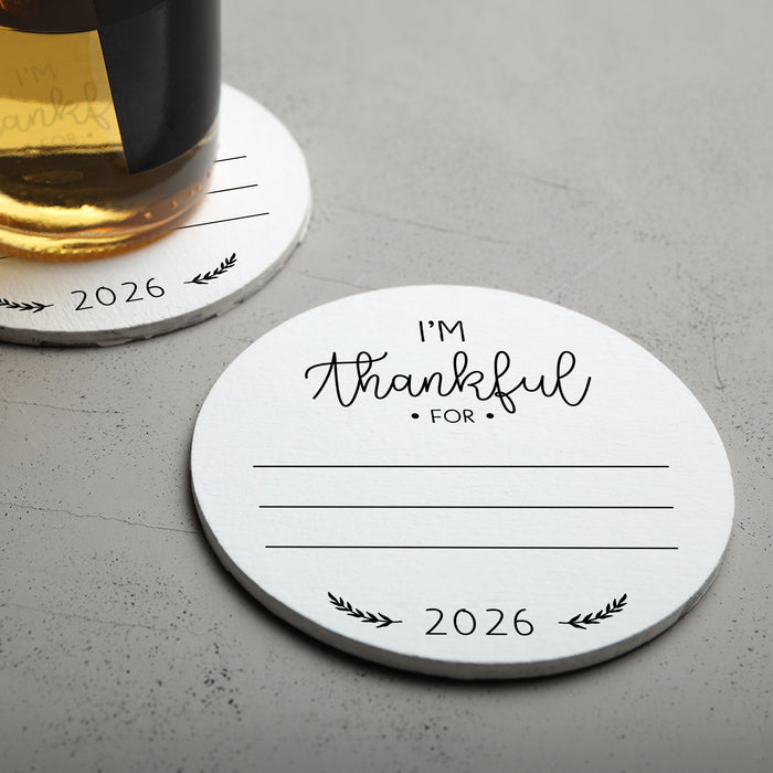 Two white Thanksgiving coasters with black text and designs. The coasters have the text "I'm Thankful for" and "2026" printed on them.