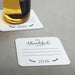 An off-white coaster with a message that says "I'm Thankful for 2026" and a beer bottle on top of it.