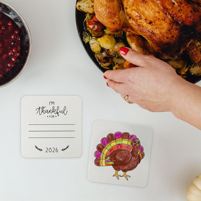 A table with a roasted turkey, cranberry sauce, and two I'm Thankful For Thanksgiving coasters.