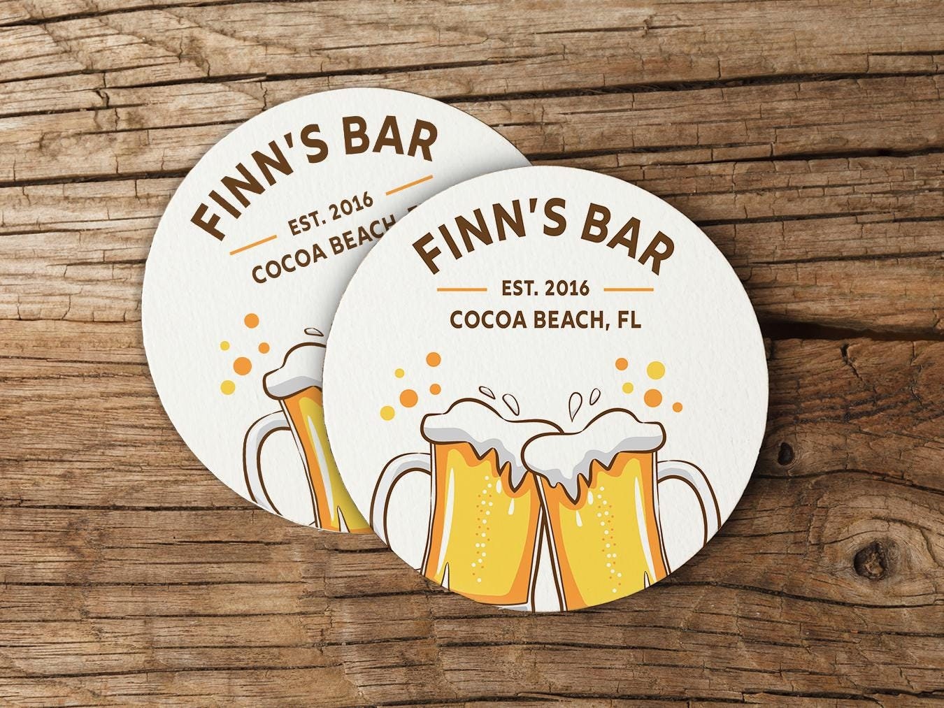 a coaster with two mugs of beer on top of it