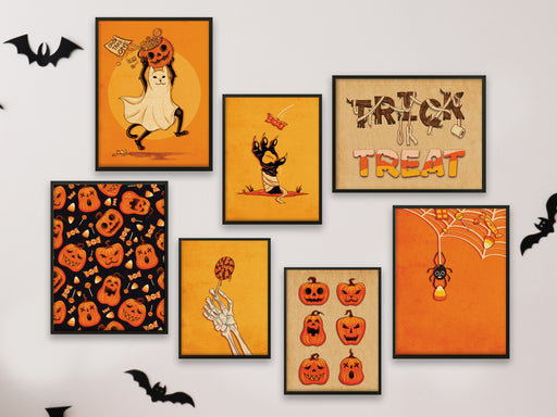 halloween art print bundle posters in frames hung up on white wall surrounded by black bat decor. Prints depict halloween spooky themes such as pumpkin patterns, cats, spiders, skeleton hands, candy, and festive typography in black and orange colors