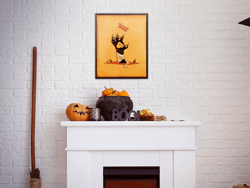 Single photo frame with retro halloween artwork of a zombie mummy cat paw grabbing a candy on white brick wall above a white fireplace hanging above halloween decoration such as pumpkins, jack o lantern, witches broom