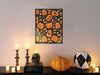 single frame with halloween pumpkin pattern and candy print hung on white wall and a countertop with halloween decoration such as candles, decorated pumpkins, and a black skull