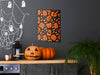 single frame with wall art above kitchen countertop and black wall with halloween decor such as ghosts, spiderwebs, and jack o lanterns with a stove, pot, and plants