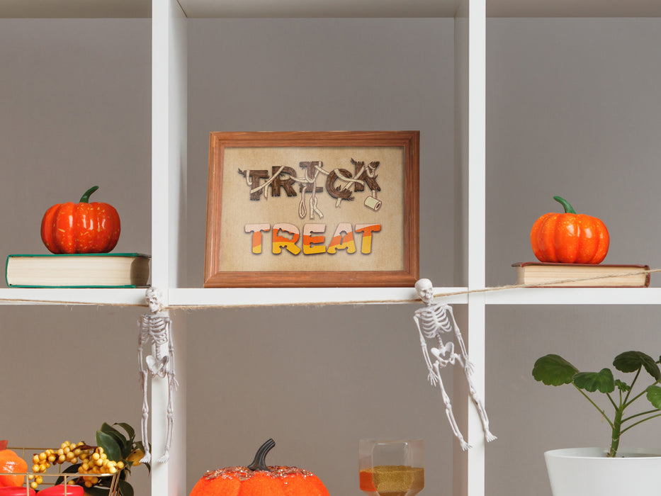 Single wooden frame with halloween typography print on decorated shelves with halloween decor such as pumpkins, skeletons, and plants