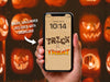 Phone Wallpaper Included with Download   Hand holding phone displaying halloween wallpaper with trick or treat typography in front of jack o lantern background