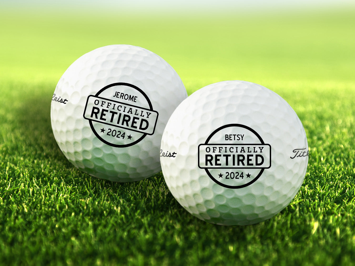 Single white Titleist golf ball with Officially Retired design on white golf tee with golf course grass in the background
