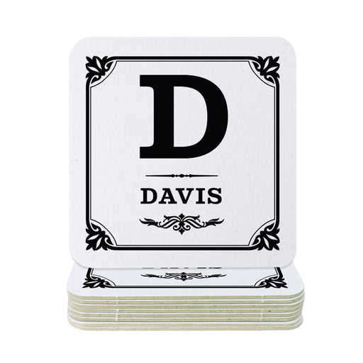 A stack of square white coasters with black printed monogram lettering and decorative borders. The top coaster shows a large black letter D above the name DAVIS.