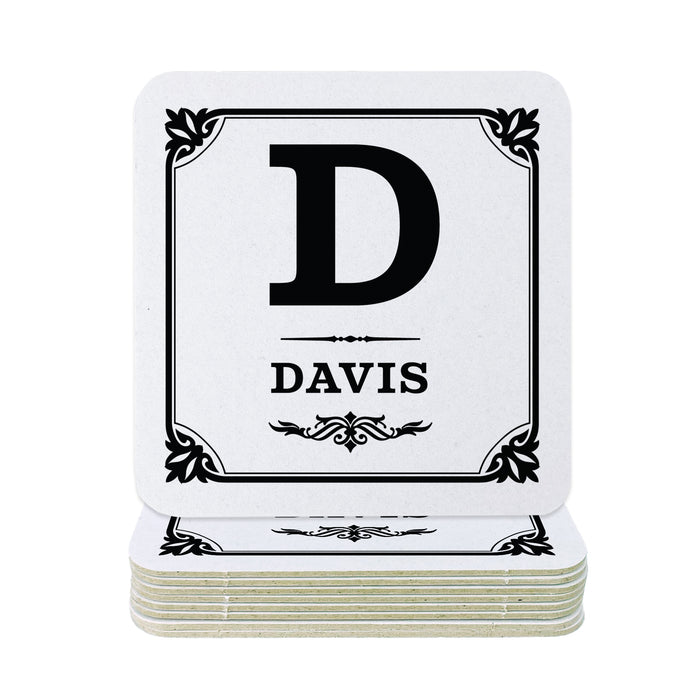 A stack of square white coasters with black printed monogram lettering and decorative borders. The top coaster shows a large black letter D above the name DAVIS.
