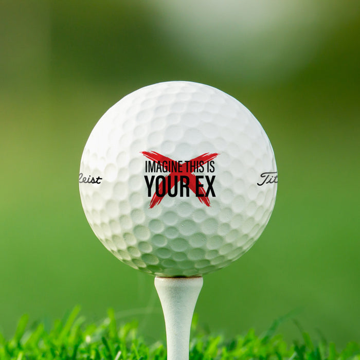 single white titleist golf ball with customizable personalized imagine this is your ex or name design on white golf tee on golf course grass background