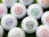 Multiple white Titleist golf balls with Officially Retired design in all available color options on golf course grass