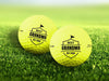 Two personalized yellow golf balls with a Best Grandma By Par design printed on them, placed on a grassy field.