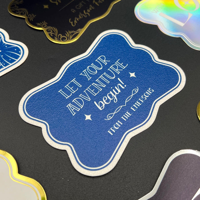 Close-up of a personalized “Let Your Adventure Begin” wedding gift tag on white glitter with navy print. The elegant cardstock tag features custom sender names with decorative wedding-inspired details.