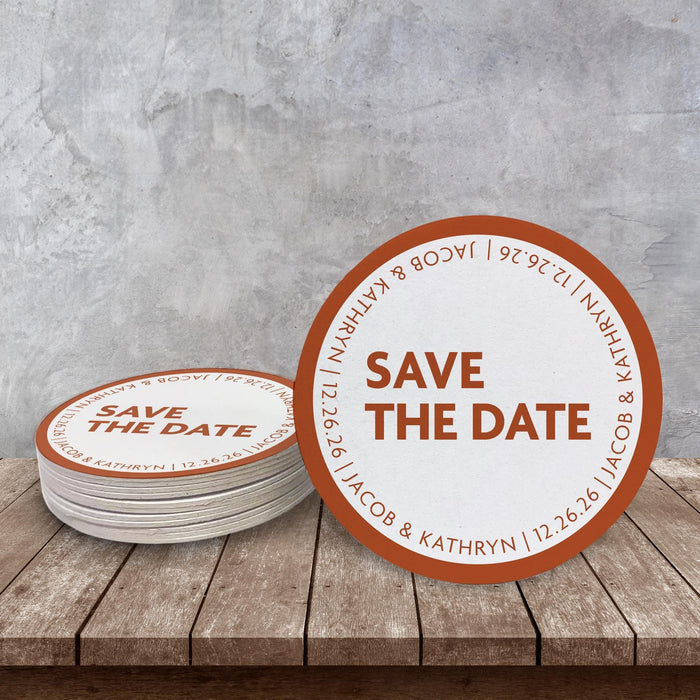Custom Save the Date coaster displayed on a rustic wood surface. Features a bold modern layout with personalized wedding details.