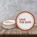Custom Save the Date coaster displayed on a rustic wood surface. Features a bold modern layout with personalized wedding details.