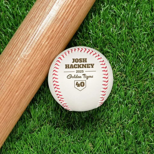 A baseball and wooden baseball bat sits on a green grassy background. The baseball has a year, player's name, number, and school name engraved into it. This design features a home plate graphic below the other text.