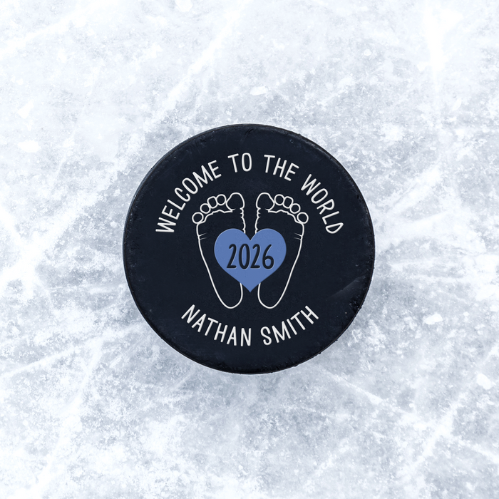 Personalized hockey puck with a UV printed baby feet birth announcement design displayed on an icy background.