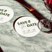 Personalized Save the Date coaster displayed beside a wine glass. Modern wedding favor customized with names and wedding date.