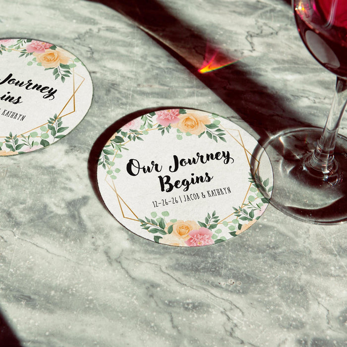 Personalized floral Save the Date coaster displayed beside a wine glass. Features a floral wedding design with custom details.